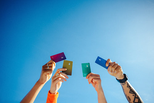 Finance supports students raising payment cards toward the sky outdoors