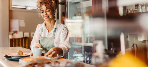 Happy female barista serving an order in a cafe