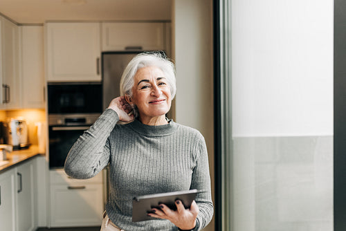 Carefree senior woman smiling while holding a digital tablet