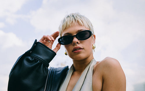 Young woman adjusts sunglasses in fashion portrait