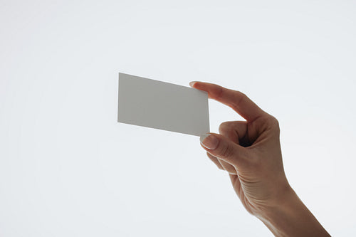 Hand holding a blank business card with a minimalistic white background