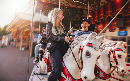 Young couple on amusement park carousel