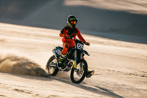 Professional motocross biker racing in sand dunes