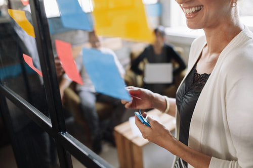 Smiling woman brainstorming using adhesive notes
