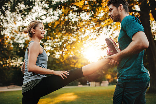Personal trainer with woman stretching in park
