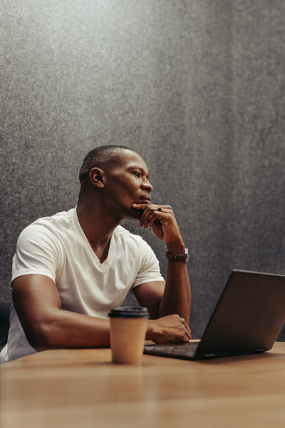 Thoughtful African man working on laptop contemplating ideas for his next creative project