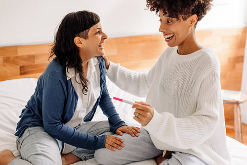 Queer couple rejoicing after taking a home pregnancy test