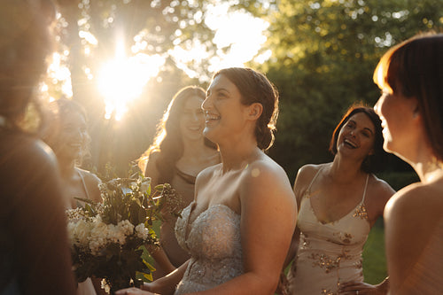 Bride celebrating with bridesmaids in sunlit garden during golden hour