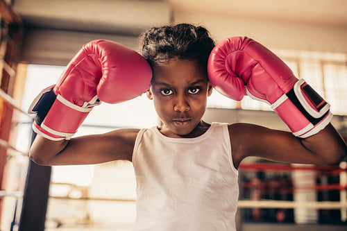 Boxing kid wearing gloves standing in a boxing gym