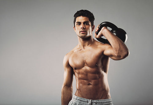 Muscular man performing crossfit workout with kettlebell
