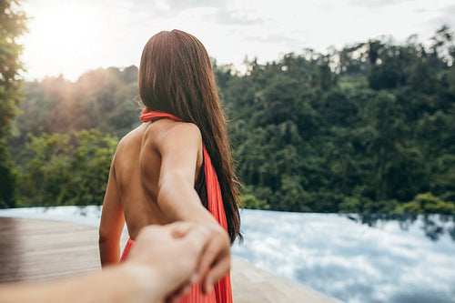 Woman holding man's hand and leads to the pool