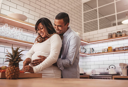 Pregnant couple cooking food together at home