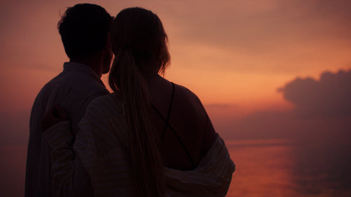 Romantic couple watches a breathtaking ocean sunset