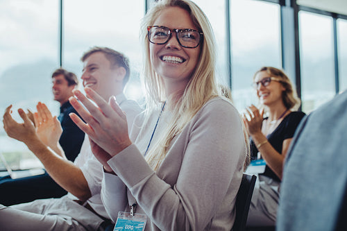 Businesspeople sitting at seminar clapping hands