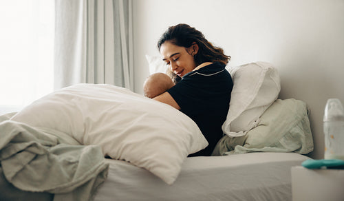 Mother embracing baby in bedroom