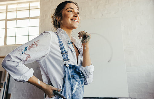 Thoughtful female painter smiling in her studio