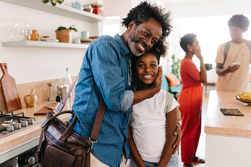 Mature dad embraces his young daughter before leaving for work in the morning