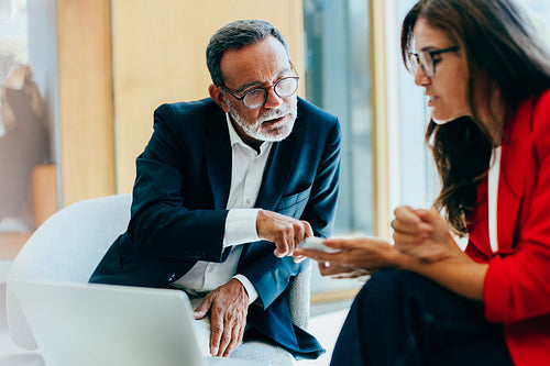 Senior manager discussing strategies with colleague during a business meeting