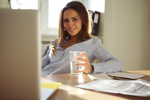 Happy young businesswoman sitting at her desk