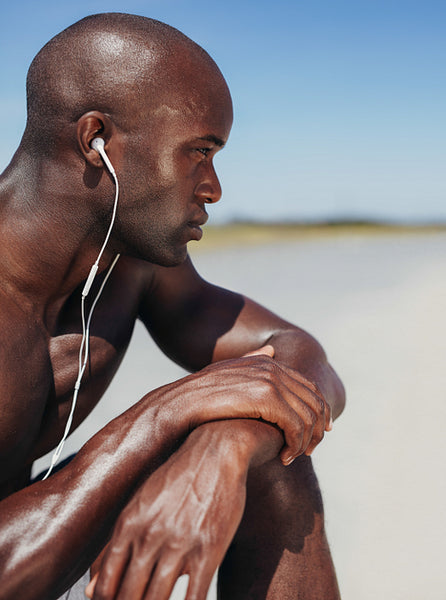 African man wearing earphones sitting alone