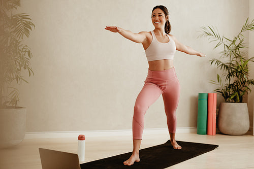 Woman doing yoga at home with laptop in front