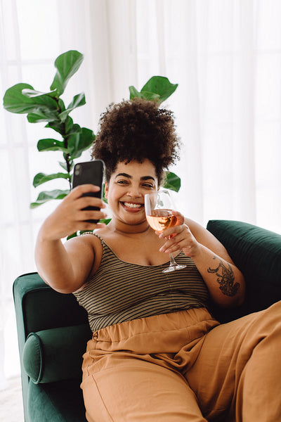 Woman with wine glass video calling friend