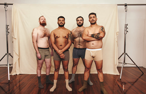 Young men standing shirtless in a modern studio