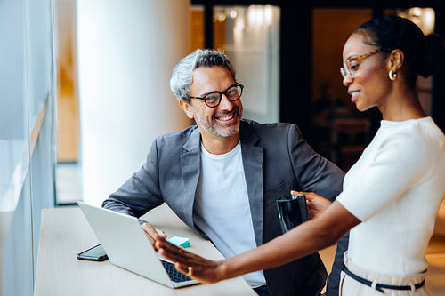 Professional coworkers having a discussion while working at a computer in an office