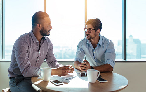 Business partners discussing business plans sitting at table in office.