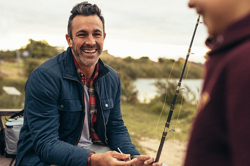 Man fishing near a lake with his kid