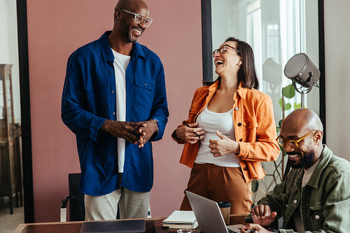Co-workers bonding in a relaxed boardroom meeting, laughing and talking in a modern workspace