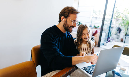 Father and daughter learn together on laptop
