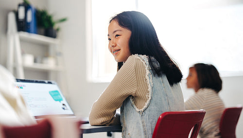 Learning to code: Girl sitting with a laptop in a computer science class