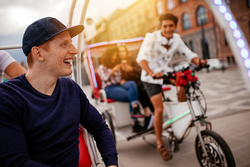Happy young man enjoying tricycle ride with friends