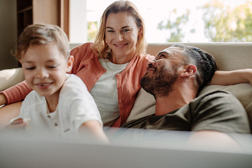 Happy young family relaxing on couch at home