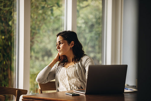 Thoughtful woman at home with laptop