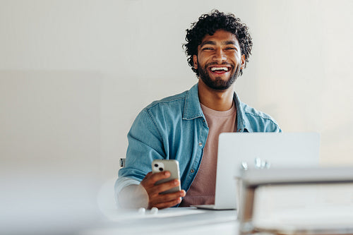 Happy young businessman working with technology for communication and connectivity in his office