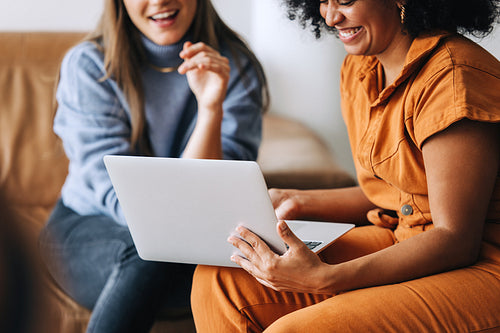 Cheerful businesswomen using a laptop together in an office lobby