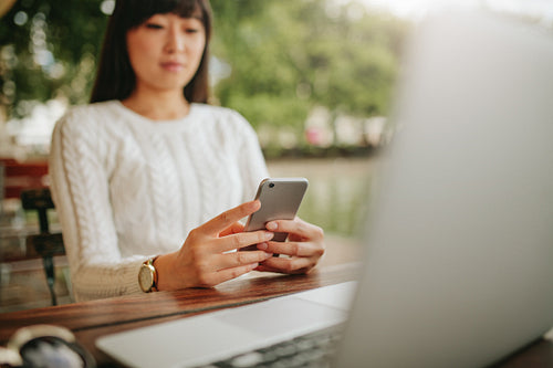 Asian woman using mobile phone at outdoor cafe