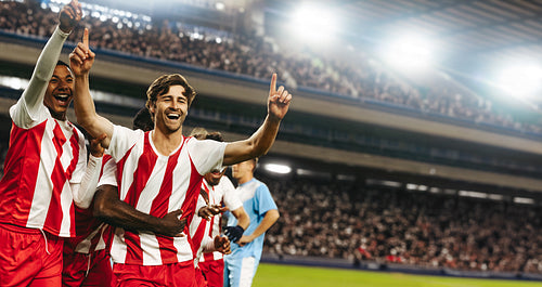 Football team celebrating victory in a professional match at a large stadium