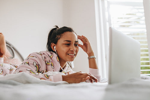 Girl using laptop lying on bed