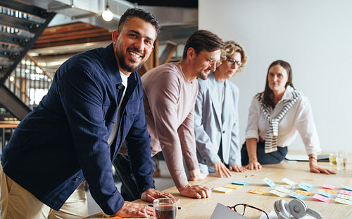 Happy business man having a meeting with his team in an advertising agency, he brainstorms with his colleagues as they prepare for a project
