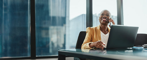 Happy businesswoman discussing with an associate on a phone call in office
