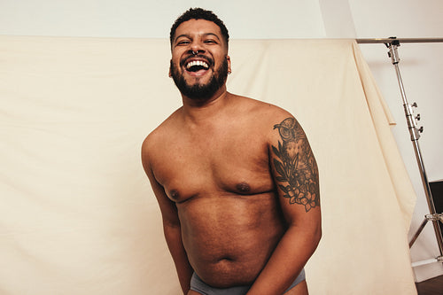 Self-confident man laughing while standing in a studio