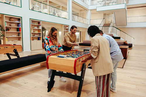 Colleagues enjoying a fun game of foosball in a modern office setting