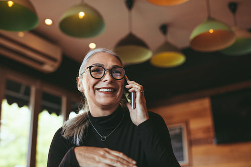 Woman talking on mobile phone at modern cafe