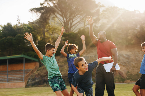 Elementary school kids celebrating with their sports coach