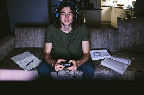Student playing video game sitting on couch at home