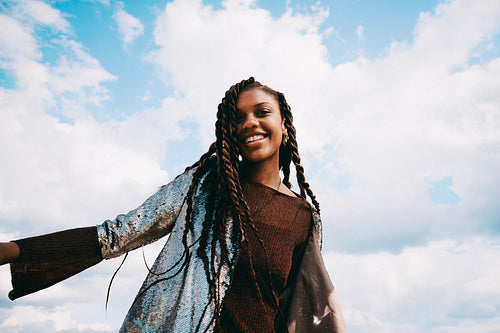 Young Black woman with braids poses under blue sky
