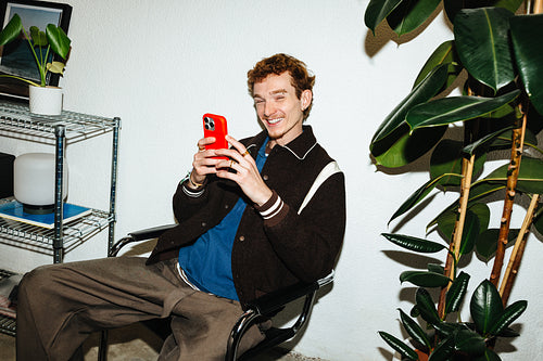Young man using smartphone at home with a happy smile in a casual interior